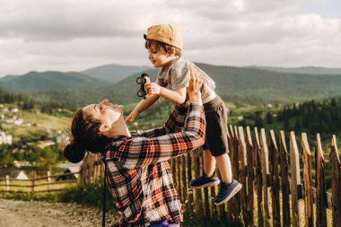 Bir anne gün batımında küçük oğlunu kollarına alır, bir dağın tepesinde durur. Yaz akşamları dağın tepesinden gelen dağ manzarası..