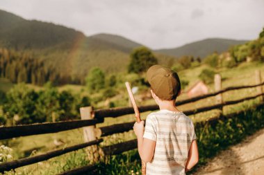 Travel to the mountains in summer. Active holidays with children in the mountains. A boy walks along a dirt road in a village in the summer in the Alpine mountains.