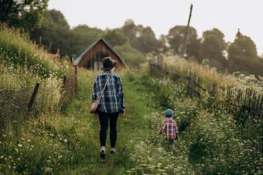 Çocuklu bir annenin aktif yaşam tarzı. Yazın dışarı çık. Çocuklarla dağlara yaz gezisi. Yazın bir dağ köyünde çocuğuyla bir annenin akşam yürüyüşü..