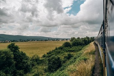 Yazın trenle dağlara seyahat et. Tren penceresinden manzara çok güzel. Yaz tatili dağlarda.