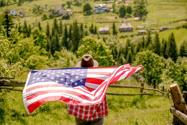 若い女性が山の上に立ち 手にアメリカ国旗を持っている アメリカ独立記念日 若いアメリカ人女性が手にアメリカ国旗を掲揚し — ストック写真