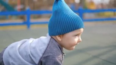 Çocuk baharda parktaki çocuk parkında sürünür. Bebeğin temiz havada aktif bir gelişimi var. Erken çocuk gelişimi. Yürüyüş yaparken bebeğin fiziksel aktivitesi..