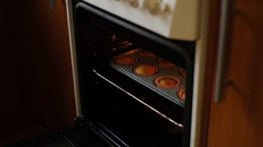 Lezzetli ev yapımı kekler. Bir kadın fırından hazır kek çıkartıyor. Büyükannem pişiriyor. Evde lezzetli ve güzel kokulu kekler pişiriyorlar..