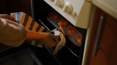 Lezzetli ev yapımı kekler. Bir kadın fırından hazır kek çıkartıyor. Büyükannem pişiriyor. Evde lezzetli ve güzel kokulu kekler pişiriyorlar..