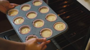 Bir kadın evde kek hazırlıyor. Ev yapımı kekler. Bir kadın fırına çiğ kekler koyuyor..