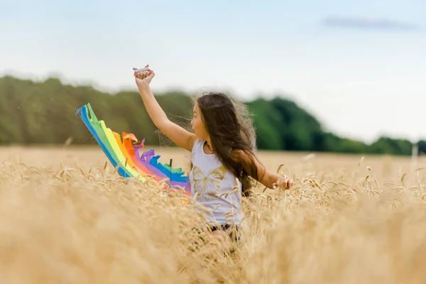 小女孩带着风筝在麦田里奔跑 计划周详而积极的周末 — 图库照片