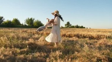 Anne ve bebek yazın tarlada yürür. Yazın açık havada aile tatili. Mutlu annelik ve mutlu çocukluk.
