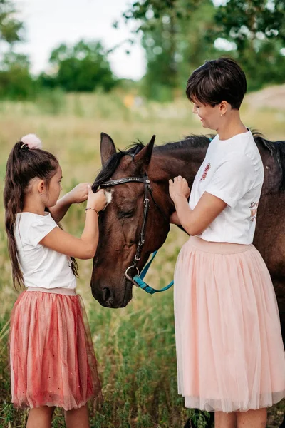 Happy childhood of a child. Communication of mother and daughter with a horse. Walk mother with daughter and horse in the summer in the forest. Psychological therapy of the child.