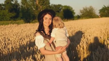 A mother with a baby walks in a wheat field in the summer at sunset. New grain crop. Overcoming the grain crisis in the world.
