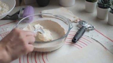 A woman prepares a sweet dessert from cottage cheese and dough in the kitchen at home. Dessert step by step. Ingredients for dessert on the table. Home kitchen.