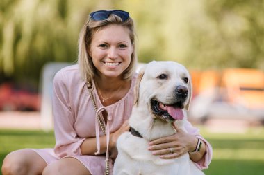 Güzel bir sarışın onu labrador retriever Park çimlerde oturuyor.