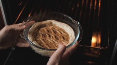 A woman puts a pie in the oven. Cooking food at home. Homemade baking. The cook puts a raw pie into the hot oven.