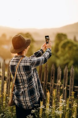 A woman travels to the mountains in summer. Evening walk in the countryside. A woman takes a selfie in the evening on a walk in the countryside.
