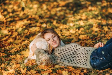 A young blonde woman is playing in the autumn park with her labrador. Evening walk with a labrador. Love for pets.