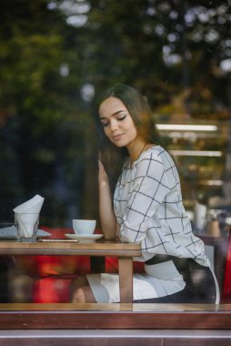 Müslümanların Avrupa 'ya entegrasyonu. Genç ve güzel Müslüman kız Avrupa kültürünü benimsiyor. Genç Müslüman bir kadın kafeteryada tesettürsüz oturuyor..