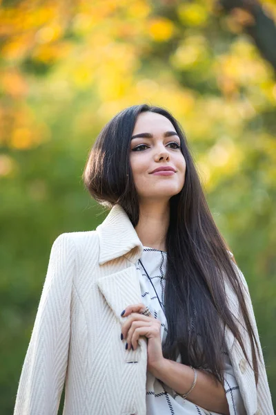 Genç güzel iş kadını sonbaharda parkta duruyor.