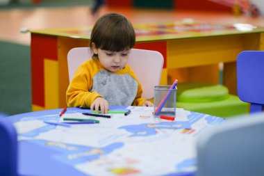 Yaratıcı bebek gelişimi. Bebek resim yapmayı öğreniyor. Çocuk Geliştirme Merkezi 'nde çocukların erken gelişimi. Mutlu çocuk çiziyor.