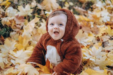 The kid sits in yellow leaves in the park for a walk. Family autumn walk in the evening in the park with children. Happy motherhood.