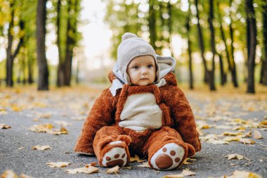 The kid sits in yellow leaves in the park for a walk. Family autumn walk in the evening in the park with children. Happy motherhood.