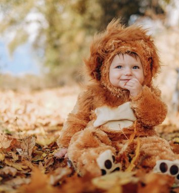 The kid sits in yellow leaves in the park for a walk. Family autumn walk in the evening in the park with children. Happy motherhood.