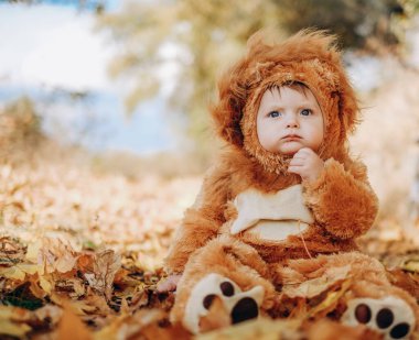 The kid sits in yellow leaves in the park for a walk. Family autumn walk in the evening in the park with children. Happy motherhood.