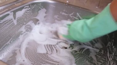 Lastik eldivenli kadın elleri mutfak lavabosunu köpük ve süngerle yıkıyor. Temizlik ve temizlik konsepti, ev hanımı.