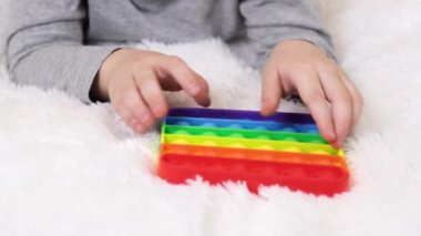 Küçük çocukların elleri eğitici bir oyun oynuyor. Rengarenk anti-stres oyuncakları. Kıpırdayın. Kıpırdayın. Stres karşıtı moda, oyuncağı patlatır. Gökkuşağı duyusal kıpırdaması. Yeni moda silikon oyuncak