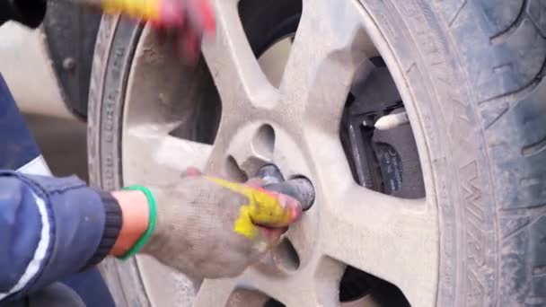 Mann mit Mühe fixiert oder dreht ein Rad an einem Auto Volvo von Hand, der Prozess der Demontage oder Befestigung eines Rades mit einem Handwerkzeug zu Hause, ein Mann die Aufgabe, Gummi an einem Auto zu ersetzen. Russland, Moskau, 16.10.2021 — Stockvideo