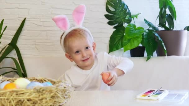 Vtipný šťastný chlapeček s velikonočními vejci a králičími ušima. Velikonoční koncept, šťastné dětství. Easter Egg Hunt. Zpomalený pohyb. — Stock video