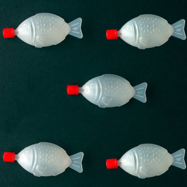 Plastik balık sürüsü. Siyah arka planda soya soslu plastik balık konteynırı. Çevresel sorun ve tek kullanımlık eşyalar. Dünya okyanusu kirliliği. Fotoğraf: Sıfır atık ve geri dönüşüm