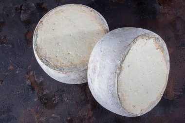 Eski çedar peyniri. Tekerlekli peynir. Koyu ahşap zeminde yıllanmış çedar peyniri çarkı.