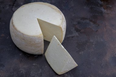 Eski çedar peyniri. Tekerlekli peynir. Koyu ahşap zeminde yıllanmış çedar peyniri çarkı.