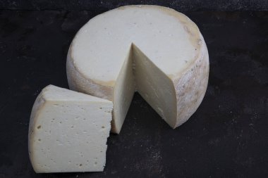 Eski çedar peyniri. Tekerlekli peynir. Koyu ahşap zeminde yıllanmış çedar peyniri çarkı.