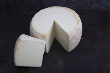 Eski çedar peyniri. Tekerlekli peynir. Koyu ahşap zeminde yıllanmış çedar peyniri çarkı.