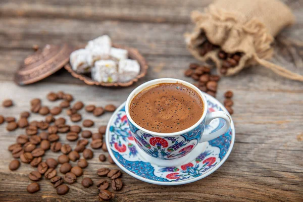 Turkish Coffee on wood table. Turkish Coffee ceramic traditional cup, coffee beans scattered on table.