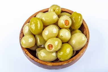 Tahta bir kasede kırmızı tatlı biberle doldurulmuş küçük yeşil zeytin turşusu. Doldurulmuş dolma biberli Olea Avrupa meyveleri. Yukarıdan yakın çekim, beyaz arkaplanda izole edilmiş, makro yiyecek fotoğrafı.