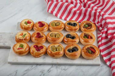 Mini Sosisliler açık büfe olarak servis edildi. Çeşitli sebzeli mini pizzalar, mozzarella peyniri ve mermer arka planda taze fesleğen, yakın plan, üst manzara..