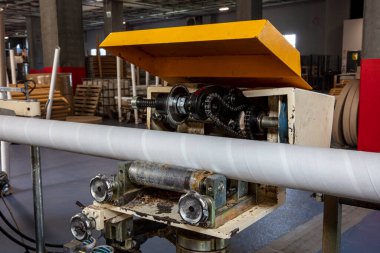 Kağıt tüp çekirdekleri için yapıştırıcı makinesi, çelik metal motor, endüstriyel üretim fabrikasında çalışan teknoloji üreticisi. Ham ürün ekipmanları. Depoda karton kargo.