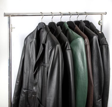 Farklı renkte deri ceketlerin yeni koleksiyonu. Dükkandaki askılarda deri ceketler var. Modern baharın renkli arka planı, sonbahar kıyafetleri. Mevsimlik giysiler indirimde..