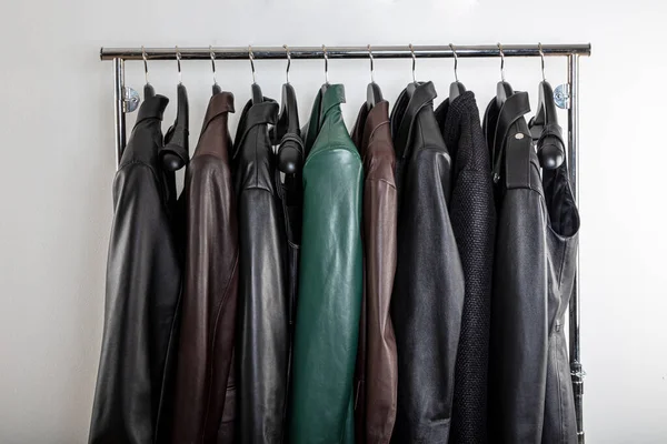 New collection of different color spring leather jackets. Leather jackets on hangers in the shop. Colorful background of modern spring, autumn outerwear. Seasonal clothing in store on sale.