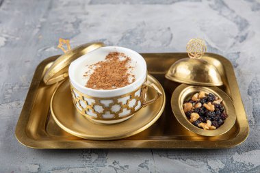 Bakır tepside Türk salamı. Tarçınlı ve fıstıklı Sahlep içeceği. Sahlep, Türkiye 'de kış aylarında çok popüler olan lezzetli bir sıcak süt içeceğidir..