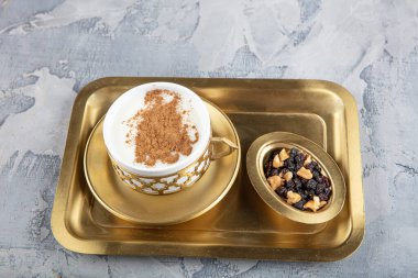 Bakır tepside Türk salamı. Tarçınlı ve fıstıklı Sahlep içeceği. Sahlep, Türkiye 'de kış aylarında çok popüler olan lezzetli bir sıcak süt içeceğidir..