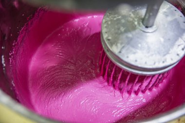 Makaron üretimi. Pembe hamurun hazırlanması. Paslanmaz bir kasede pembe tereyağlı makarna. Modern gümüş mutfak tezgahı karıştırıcısı badem kurabiyesi için hamur karıştırıyor..