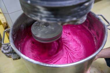 Makaron üretimi. Pembe hamurun hazırlanması. Paslanmaz bir kasede pembe tereyağlı makarna. Modern gümüş mutfak tezgahı karıştırıcısı badem kurabiyesi için hamur karıştırıyor..