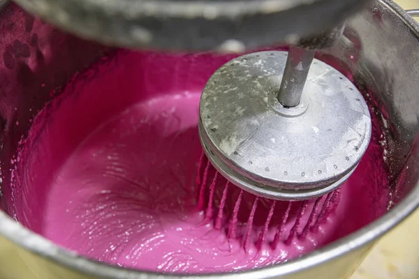 Makaron üretimi. Pembe hamurun hazırlanması. Paslanmaz bir kasede pembe tereyağlı makarna. Modern gümüş mutfak tezgahı karıştırıcısı badem kurabiyesi için hamur karıştırıyor..