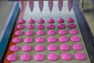 Makaron üretimi. Pembe hamurun hazırlanması. Paslanmaz bir kasede pembe tereyağlı makarna. Modern gümüş mutfak tezgahı karıştırıcısı badem kurabiyesi için hamur karıştırıyor..