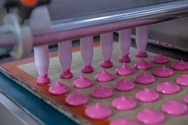 Makaron üretimi. Pembe hamurun hazırlanması. Paslanmaz bir kasede pembe tereyağlı makarna. Modern gümüş mutfak tezgahı karıştırıcısı badem kurabiyesi için hamur karıştırıyor..