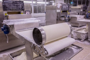 Baker hamur kalıbından hamur işi yapıyor. Hamur, ekmek ve baklava üretimi için hamur rulosu makinesi.