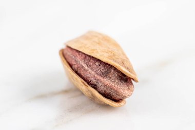 Kabukta şam fıstığı yığını var. Fıstık mermer zemin üzerinde izole.