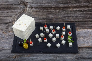 Tahta kesme tahtasındaki Feta Peynir Küpleri. Tahtada bıçakla izole edilmiş kare küp beyaz peynir..